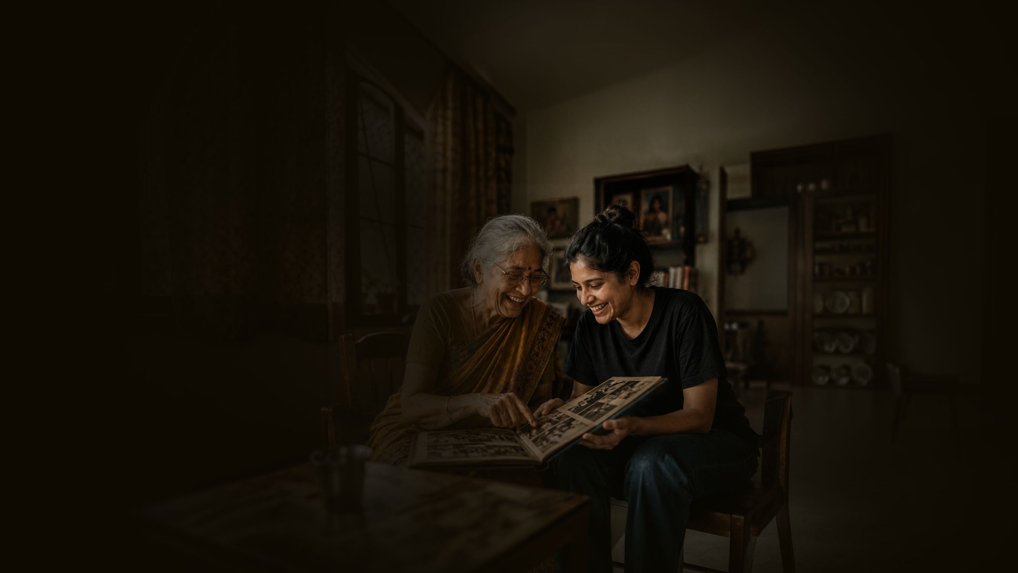 Grandmother and companion laughing together over an old photo album