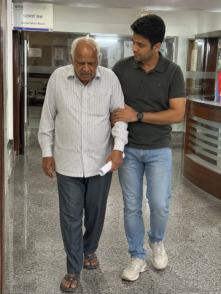 Companion walking with an elderly man down a hospital corridor